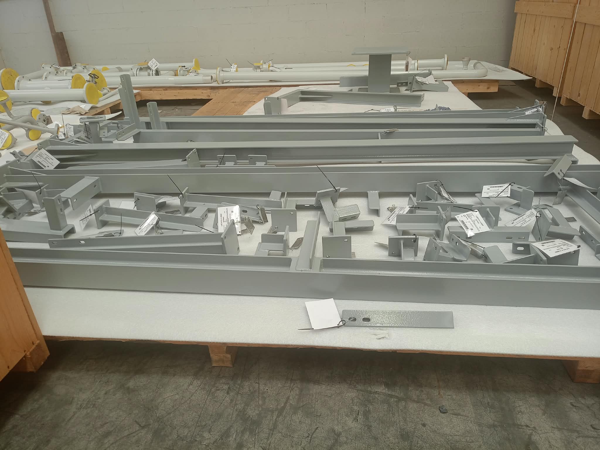 Componenti metallici verniciati disposti su pedana in legno con protezione